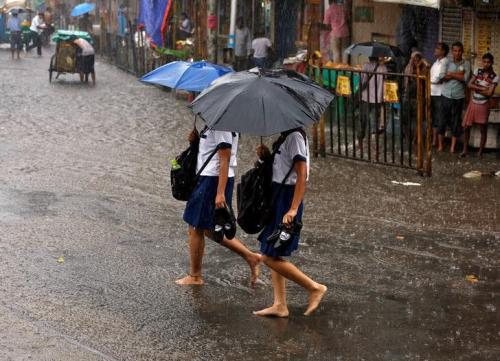 School girls walk barefoot as they cross a waterlogged road during rains in Kolkata, July 25, 2016. REUTERS/Rupak De Chowdhuri/Files